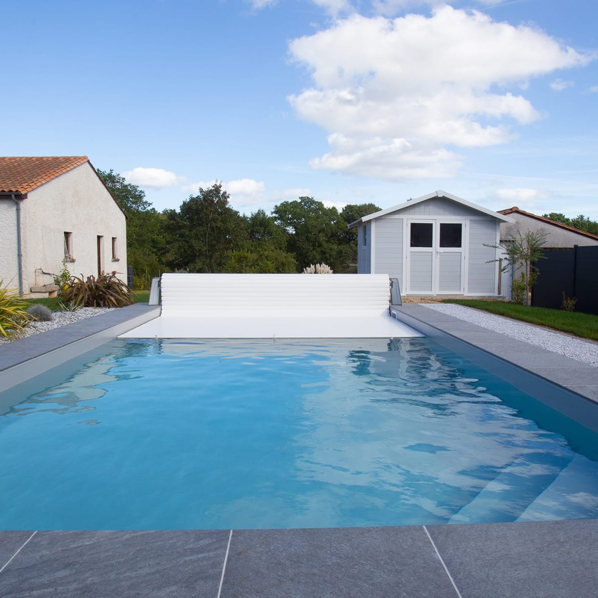 Piscine extérieure avec escalier d'angle, liner gris et margelles grès cérame, volet hors-sol